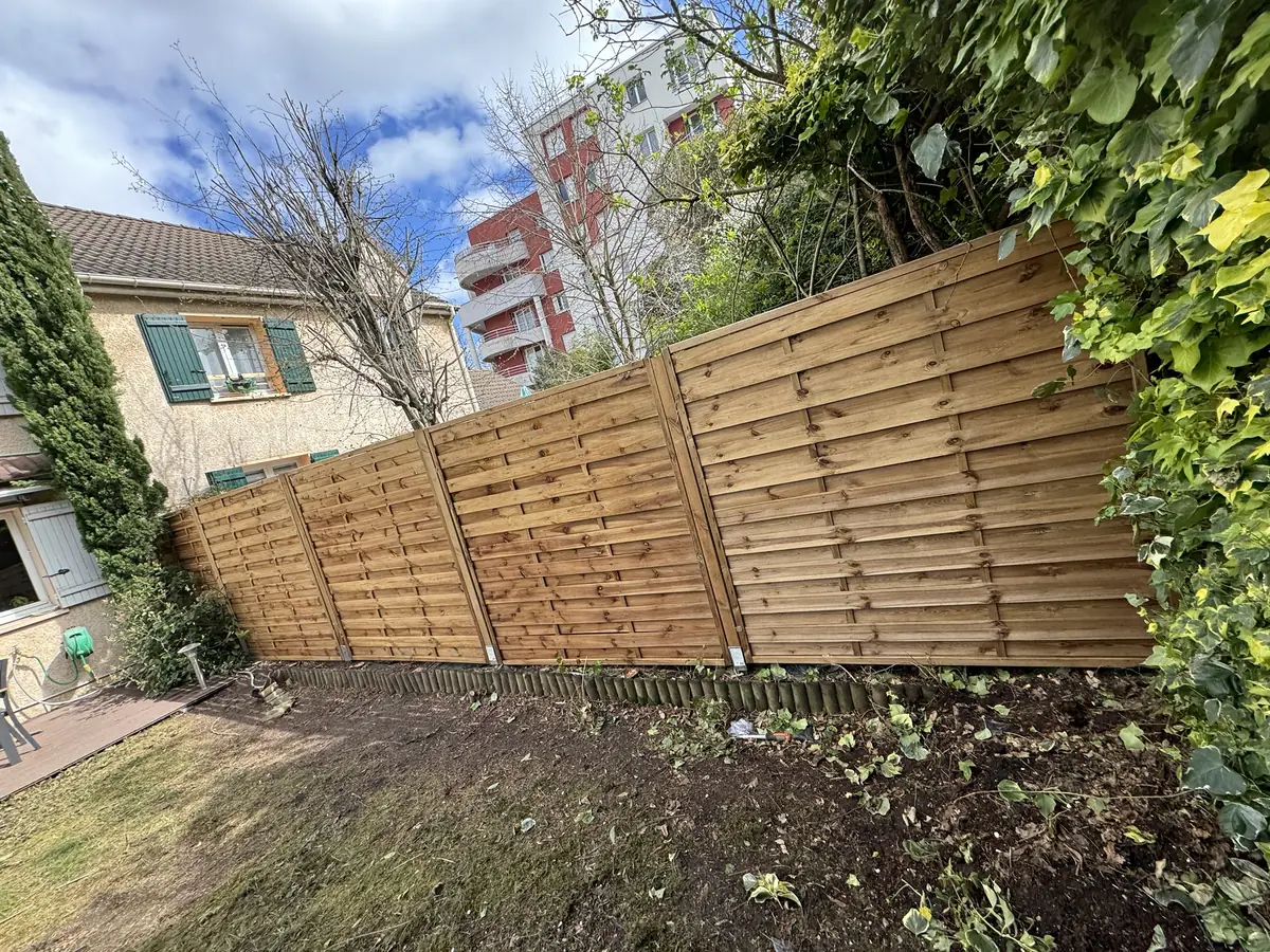 Clôture en panneaux de bois posée dans un jardin