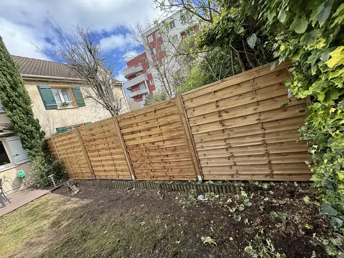Clôture en panneaux de bois posée dans un jardin
